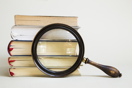Vintage magnifying glass and stack of booksの写真素材