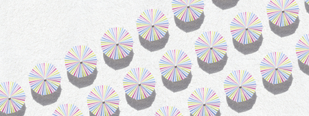 Colorful umbrellas on white sand - top view