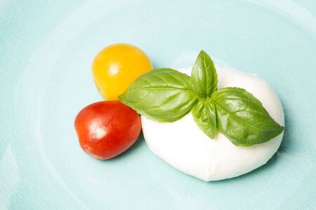 Mozzarella, basil and cherry tomato on blue backgroundの写真素材