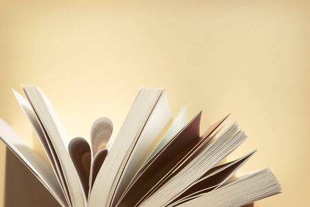 Open book over yellow background close up