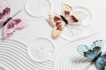 White sand pattern with colorful butterfliesの写真素材
