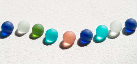 Colorful marbles on white sand backgroundの写真素材