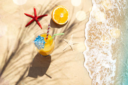 Summer background with cocktail and starfish on sandの写真素材