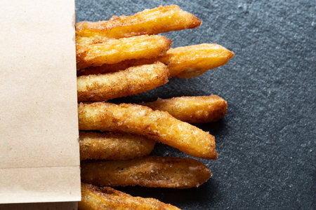Churro stick with chocolate on black granite board