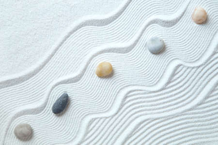 Zen garden with peble stones on white sand patternの写真素材