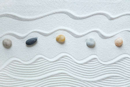 Zen garden with pebble stones on white sand patternの写真素材