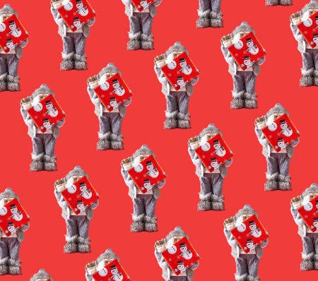 Pattern made of Santa holding gift box against red background. Minimal Christmas concept. Creative pattern idea.の写真素材
