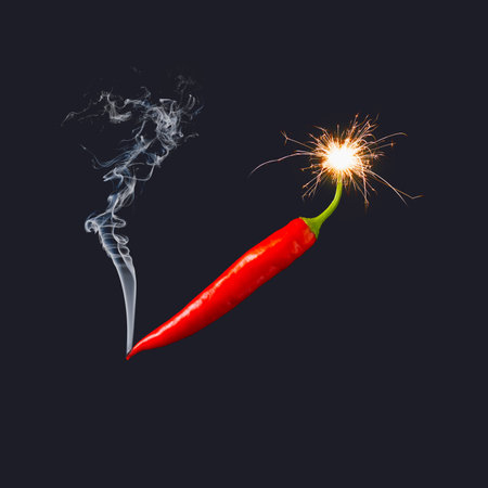 Red hot chilli pepper with sprinkler and smoke, against black background. Minimal creative idea.