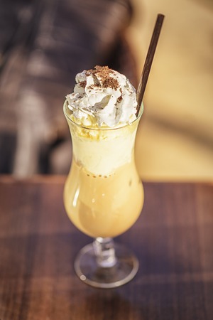 Ice coffee in a big glass cup, whipped cream, black straw