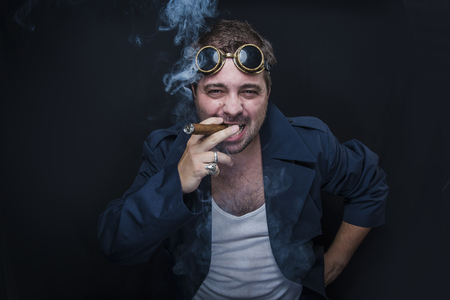 Grunge man, steampunk dressed, smoking a cuban cigarの写真素材