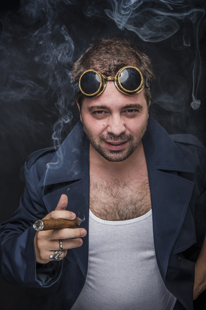 Grunge man, steampunk dressed, smoking a cuban cigarの写真素材