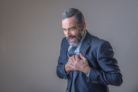 Senior business man experiencing strong chest pain or a heart-attackの写真素材