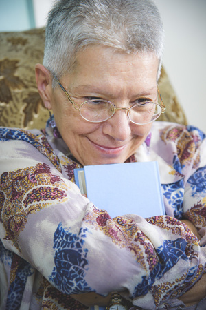 Senior woman holding her favorite book, remembering old loveの写真素材