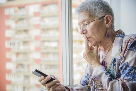 Senior elderly woman having troubles with her cell phone, cant establish the connectionの写真素材