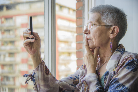Senior elderly woman having troubles with her cell phone, cant establish the connectionの写真素材