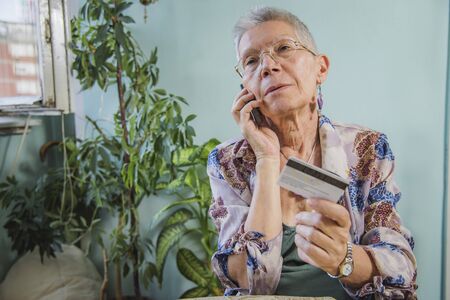Senior lady arguing with a bank clerk over her credit card balanceの写真素材