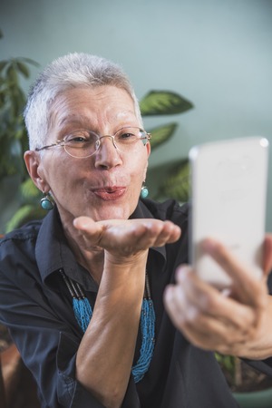Old woman using social media apps to connect with her distant relatives, or friends overseasの写真素材