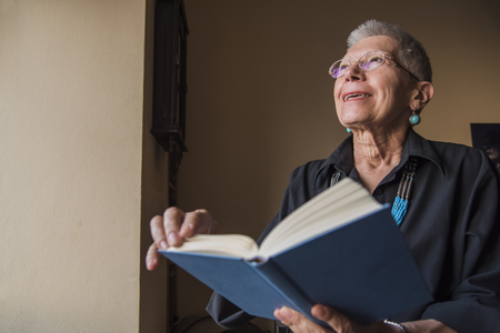 Senior woman holding her favorite book, remembering old loveの写真素材