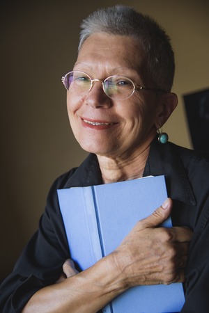 Senior woman holding her favorite book, remembering old loveの写真素材