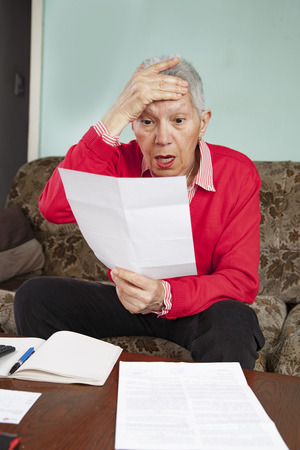 Senior old woman shocked with the bills she receives, appalled and gaspingの写真素材