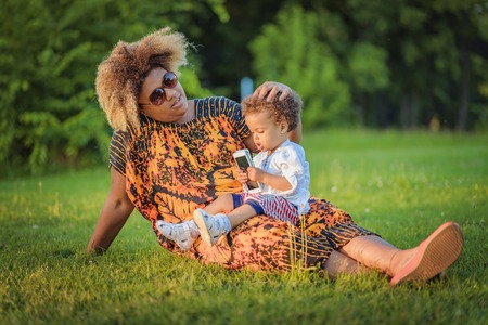 African american mother with her mixed race daughter laughing in the park, enjoying a beautiful day outsideの写真素材