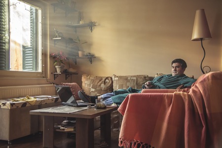 Mature man watching tv in his living room, dressed in bathrobeの写真素材