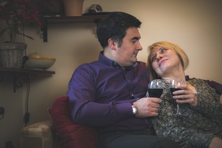 Husband and wife having a toast with glasses of red wine, celebrating anniversary or valentines dayの写真素材
