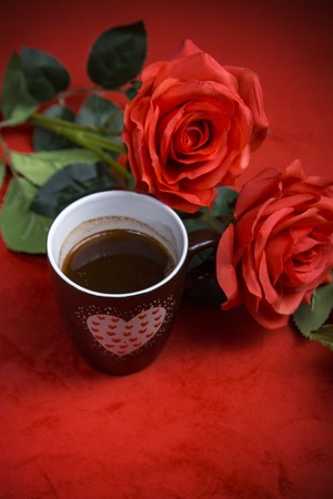 Valentines day celebration with romantic items: sealed love letter, a rose, a heart cup on a dark red backgroundの写真素材