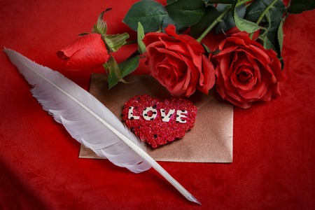 Love letter for valentine, romantic setup with a quill and an envelope on a dark red backgroundの写真素材
