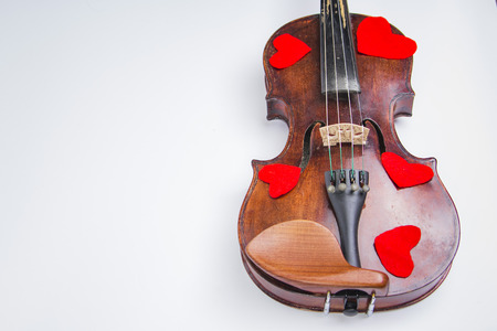 Romantic antique instrument, a violin covered with red heart shapes and roses, white backgroundの写真素材