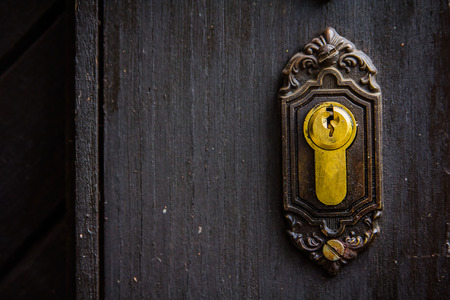 Golden keyhole on a rusty vintage wooden door