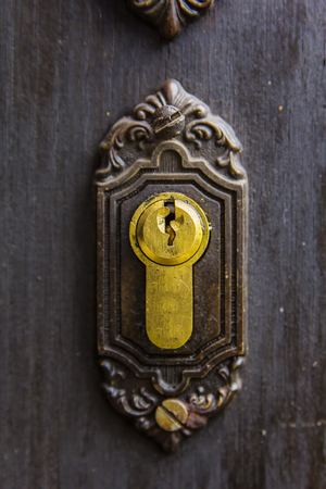 Golden keyhole on a rusty vintage wooden doorの写真素材