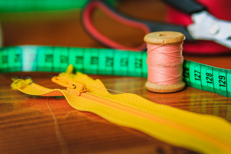 Clothing tools and accessories, scissors, measuring tape, and a roll of threadの写真素材