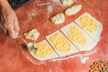 Senior old man hands wrapping small pastry dough with cheeseの写真素材
