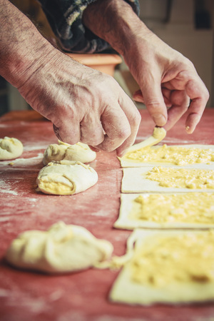 Senior old man hands wrapping small pastry dough with cheeseの写真素材