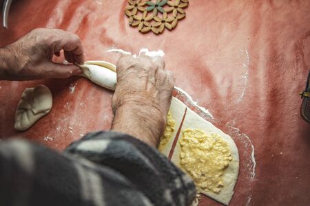 Senior old man hands wrapping small pastry dough with cheeseの写真素材