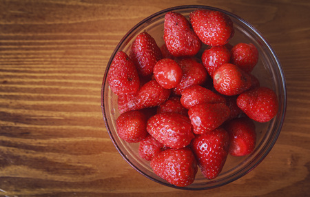 Glass bowl full of pealed and clean fresh strawberries on a wooden surfaceの写真素材