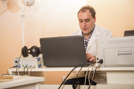 Young doctor doing some work on his laptop in his office, clinic workの写真素材
