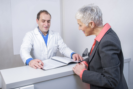 Senior woman paying her medical bill at the clinic with her credit cardの写真素材