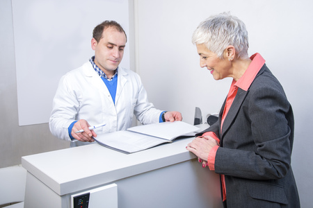 Senior woman paying her medical bill at the clinic with her credit cardの写真素材
