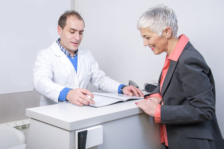 Senior woman paying her medical bill at the clinic with her credit cardの写真素材