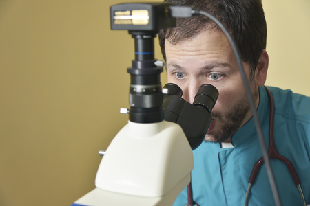 Young handsome doctor shocked with his microscope findingsの写真素材