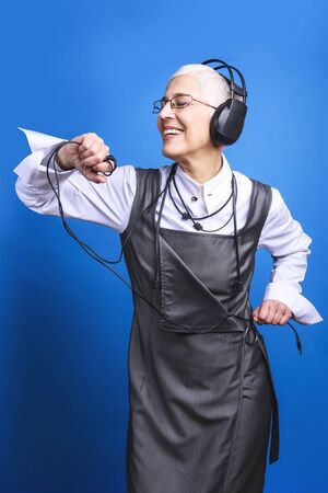 Senior old woman listening to her favorite music through big headphones, enjoying the rich soundの写真素材