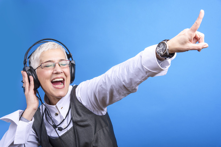 Senior old woman listening to her favorite music through big headphones, enjoying the rich sound