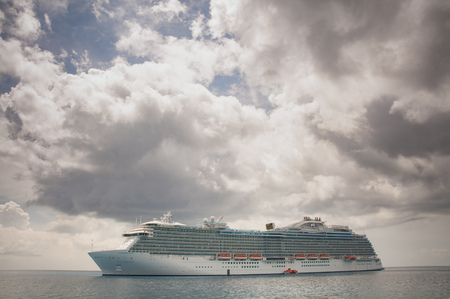 MARCH, 2015 - ST. THOMAS, CARIBBEAN: Big cruise ship docked in the middle of the ocean on the clear water, dramatic sky and sunのeditorial素材