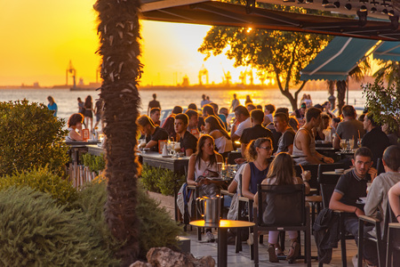 AUGUST 2017, THESSALONIKI GREECE: Sunset view of people sitting in a coffee shop, enjoying a late afternoon togetherのeditorial素材