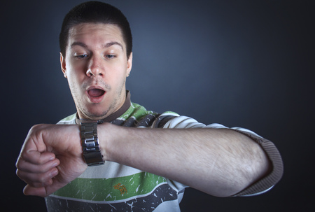 Young man shocked with the time, gasping at realizing what time it isの写真素材