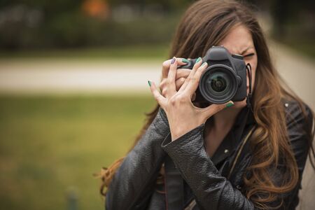 Young professional or amateur photographer taking a picture with her dslr cameraの写真素材