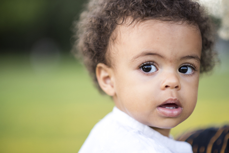 Adorable little mixed race girl having fun in the park, green grass and sunny dayの写真素材
