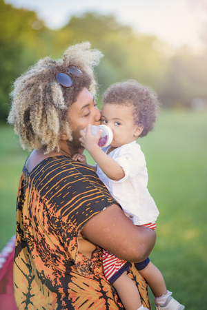 Mother and daughter, african american and mixed race, playing together in a park on a bright sunny dayの写真素材